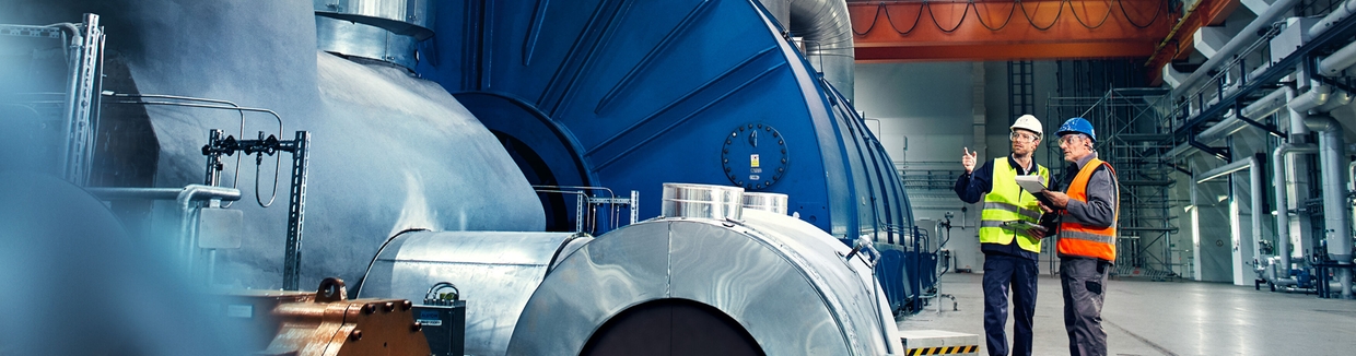 Imagem de um engenheiro em frente a uma turbina na fabrica de energia