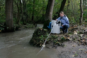 Uma mulher monitora a qualidade da água de um rio em uma floresta